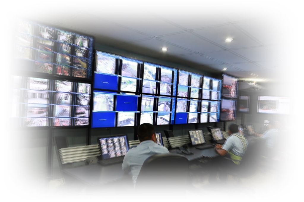 Centro de control de una C.R.A. con tres hombres trabajando en ella controlando las múltiples pantallas de videovigilancia